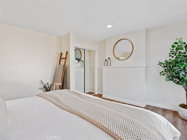 bedroom with a closet, baseboards, wood finished floors, and recessed lighting