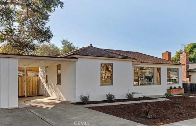 exterior space with roof with shingles, fence, and stucco siding