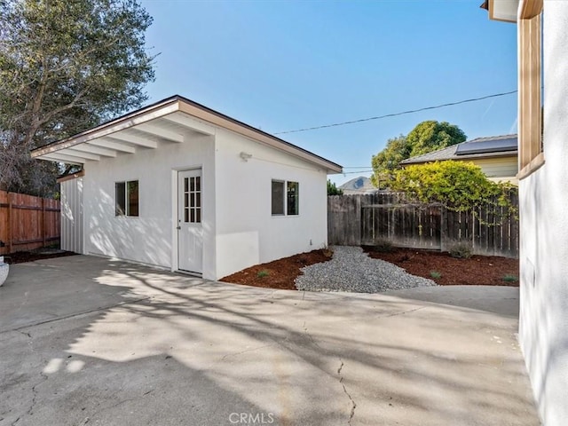 view of side of home featuring a patio area, fence, and stucco siding