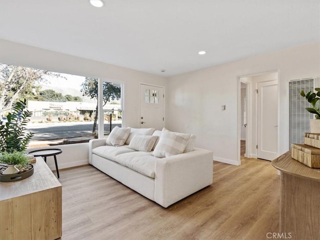 living room featuring light wood-type flooring, baseboards, and recessed lighting