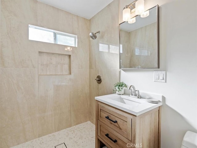 full bath with toilet, tiled shower, and vanity