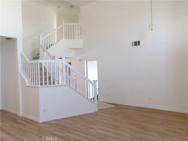 stairs featuring hardwood / wood-style floors and a towering ceiling