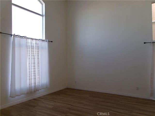 empty room featuring plenty of natural light and dark hardwood / wood-style flooring