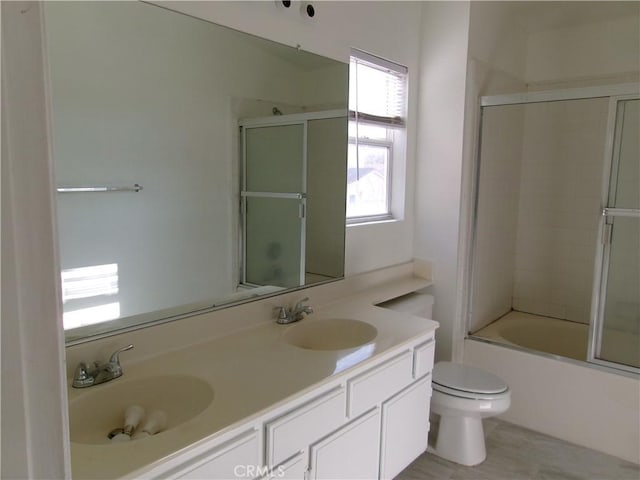 full bathroom with combined bath / shower with glass door, toilet, and vanity