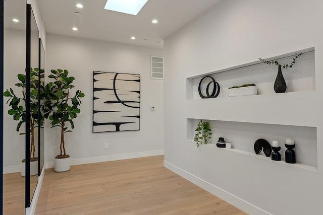 hall featuring light hardwood / wood-style flooring and a skylight