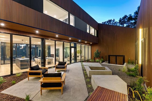 patio terrace at dusk with an outdoor living space with a fire pit