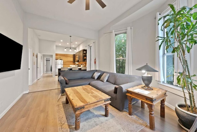 living room with lofted ceiling, ceiling fan, and light wood-type flooring