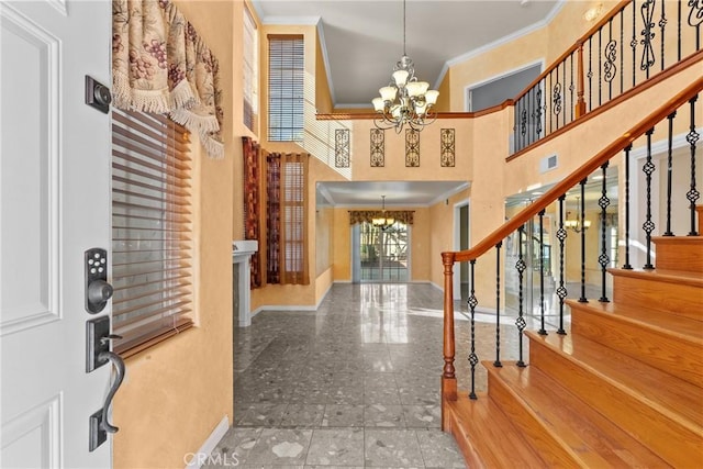 foyer entrance featuring a high ceiling, ornamental molding, and a chandelier