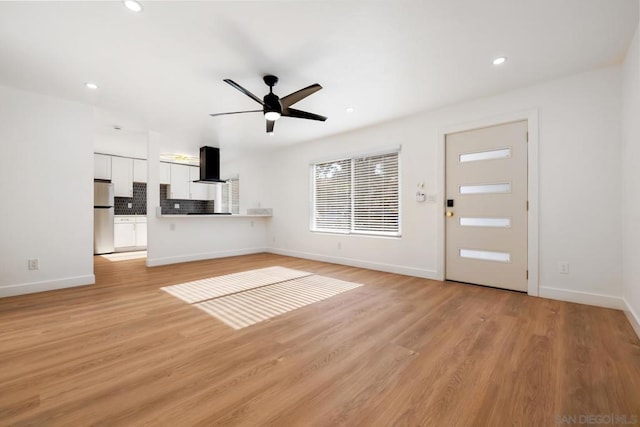 unfurnished living room featuring ceiling fan and light hardwood / wood-style floors