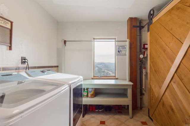 washroom with laundry area, a barn door, light tile patterned flooring, and washing machine and dryer