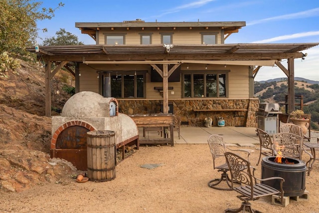 back of house featuring stone siding and a patio area