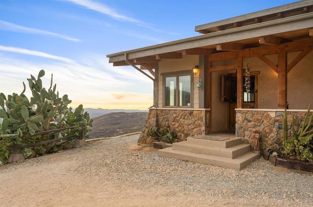 view of exterior entry with stone siding and a mountain view