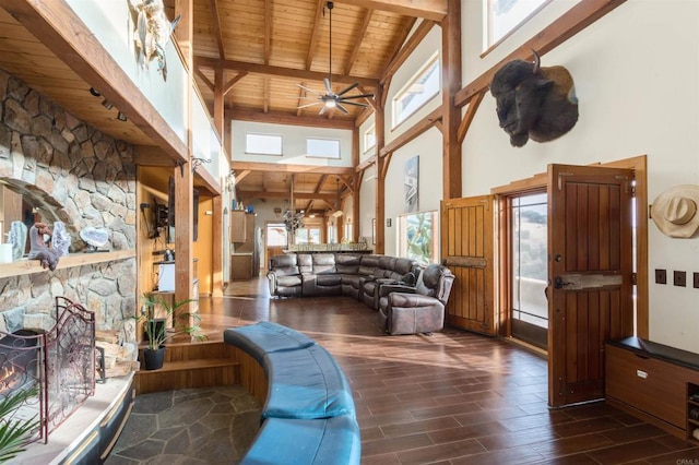 living room featuring a stone fireplace, dark wood-style flooring, wooden ceiling, and a wealth of natural light