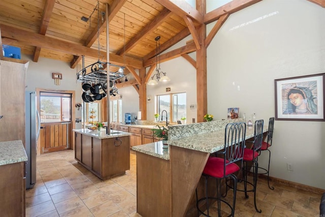 kitchen featuring a peninsula, plenty of natural light, beam ceiling, and freestanding refrigerator