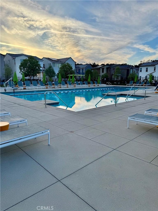 pool at dusk featuring a patio