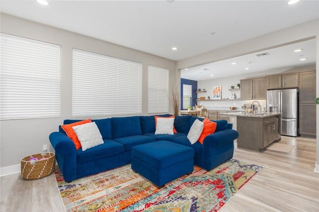 living room featuring sink and light hardwood / wood-style flooring