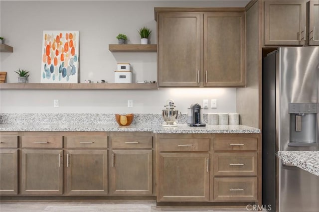 kitchen featuring stainless steel fridge with ice dispenser and light stone countertops