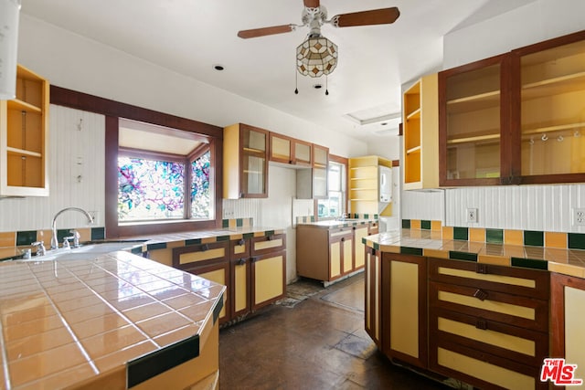 kitchen featuring sink, ceiling fan, and tile countertops