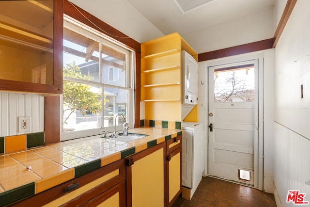 interior space featuring sink, stacked washer and clothes dryer, and tile counters