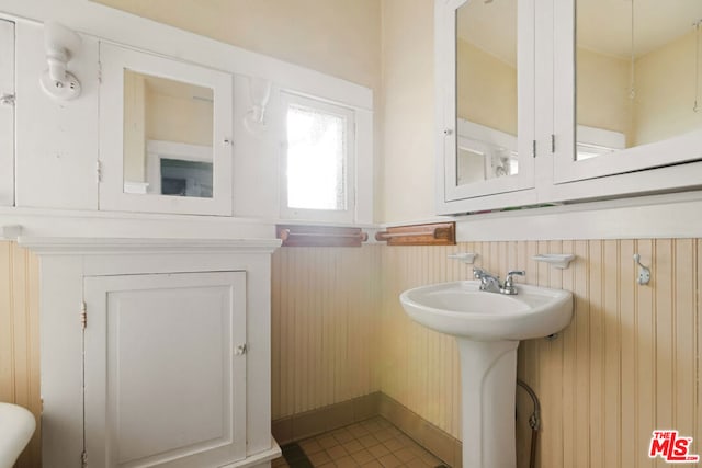 bathroom with sink, tile patterned floors, and wooden walls