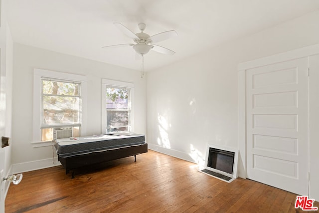 bedroom featuring ceiling fan, hardwood / wood-style floors, and cooling unit