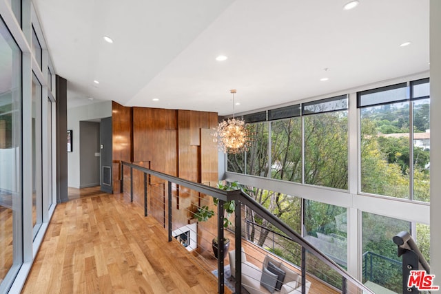 hall featuring plenty of natural light, an inviting chandelier, and light hardwood / wood-style floors