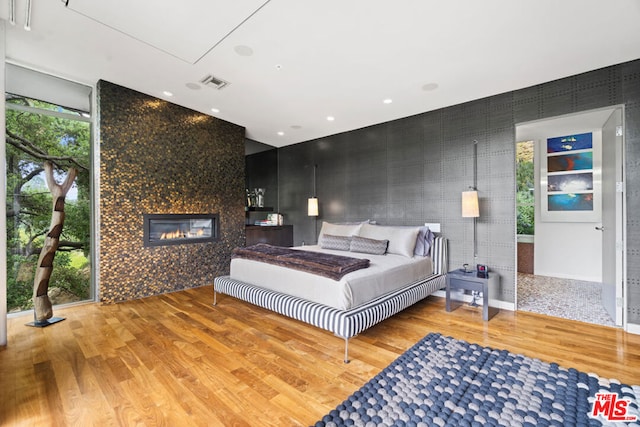 bedroom with multiple windows, a fireplace, and wood-type flooring