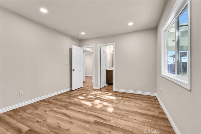 unfurnished bedroom featuring light wood-type flooring and ensuite bathroom