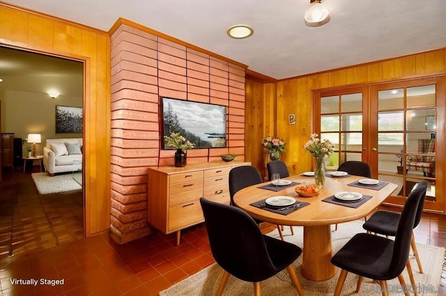 dining room featuring crown molding, french doors, dark tile patterned floors, and wood walls