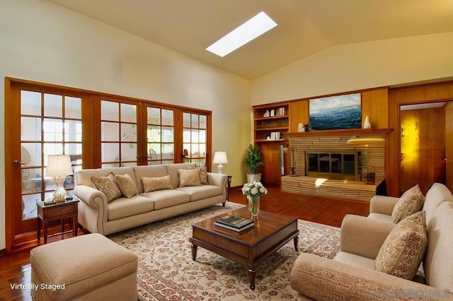 living room with a healthy amount of sunlight, vaulted ceiling with skylight, and hardwood / wood-style floors