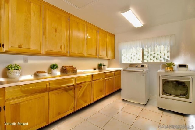 clothes washing area featuring light tile patterned floors, cabinets, and washer and dryer