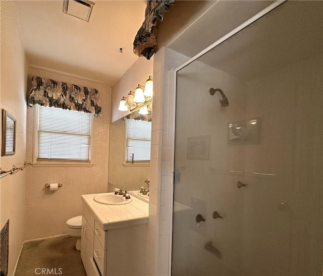 bathroom with a shower with door, toilet, and vanity