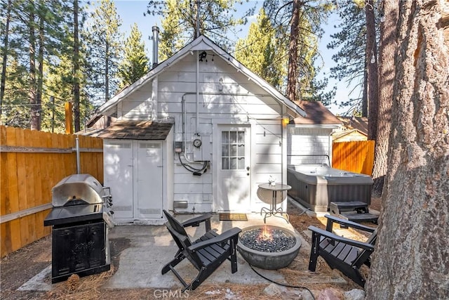 rear view of house with an outdoor fire pit, a shed, and a hot tub