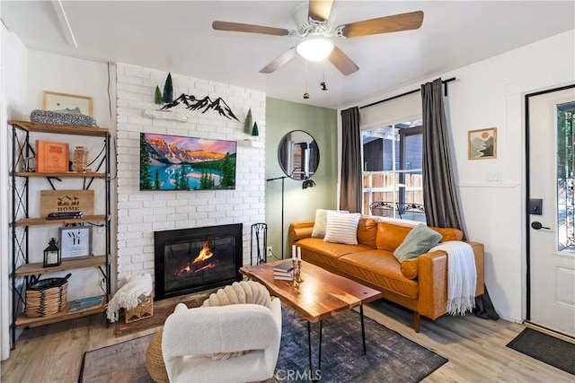 living room featuring light hardwood / wood-style floors, ceiling fan, and a fireplace