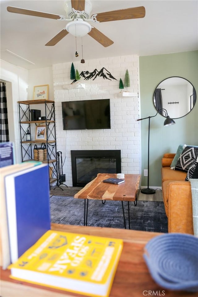 living room featuring ceiling fan, hardwood / wood-style floors, and a fireplace