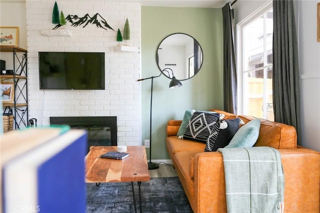 living room with hardwood / wood-style floors and a brick fireplace