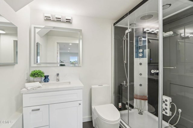 bathroom featuring a shower with shower door, toilet, and vanity