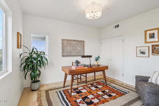 office with baseboards, visible vents, a notable chandelier, and wood finished floors