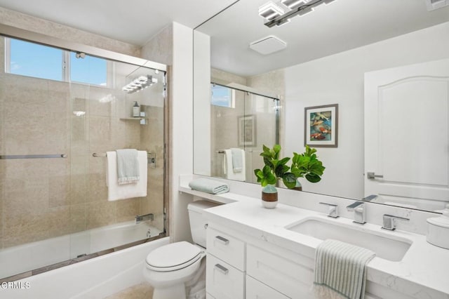 full bath with plenty of natural light, combined bath / shower with glass door, toilet, and vanity