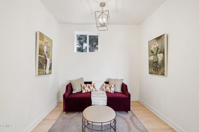 living area featuring baseboards, wood finished floors, and a chandelier