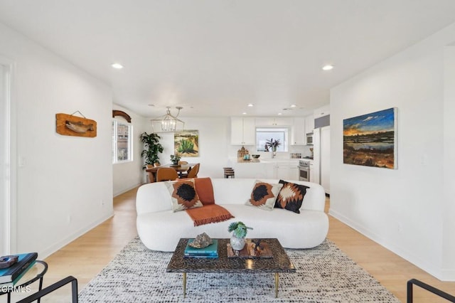 living area featuring an inviting chandelier, a wealth of natural light, light wood finished floors, and recessed lighting
