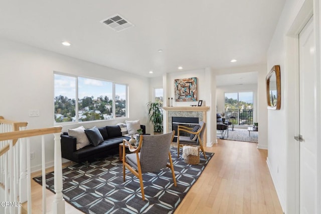 living area with visible vents, a high end fireplace, baseboards, recessed lighting, and hardwood / wood-style floors