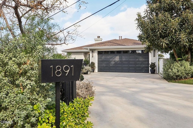 single story home with a garage, driveway, stucco siding, and a chimney