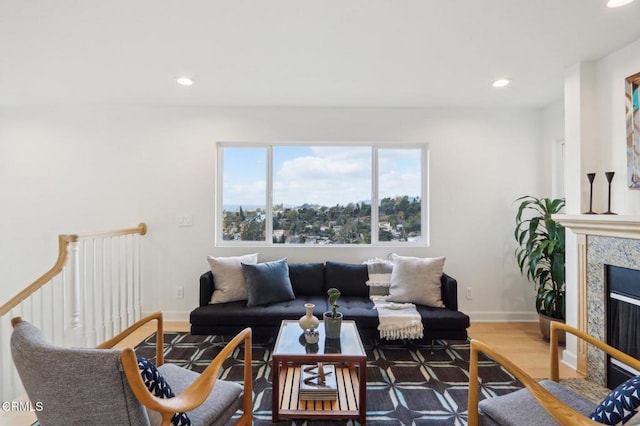 living room with a high end fireplace, recessed lighting, baseboards, and wood finished floors