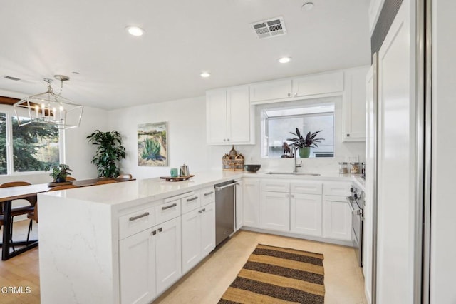 kitchen featuring a sink, visible vents, a peninsula, a notable chandelier, and appliances with stainless steel finishes
