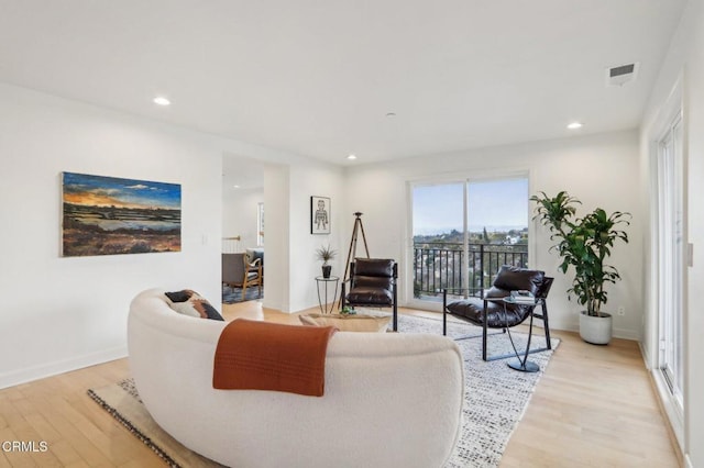 living room featuring visible vents, baseboards, light wood finished floors, and recessed lighting
