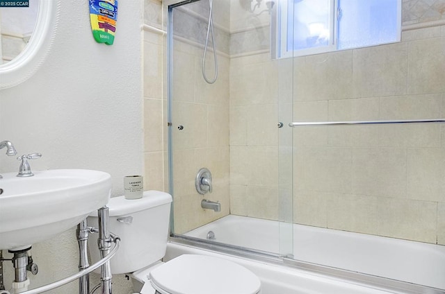 full bathroom with enclosed tub / shower combo, sink, and toilet