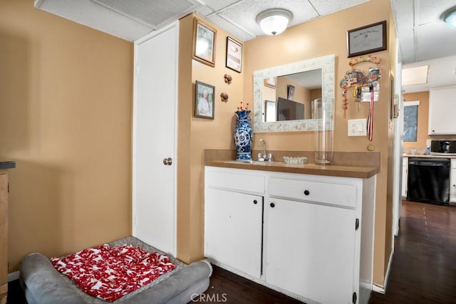 interior space featuring white cabinets, dishwasher, dark hardwood / wood-style flooring, sink, and a drop ceiling