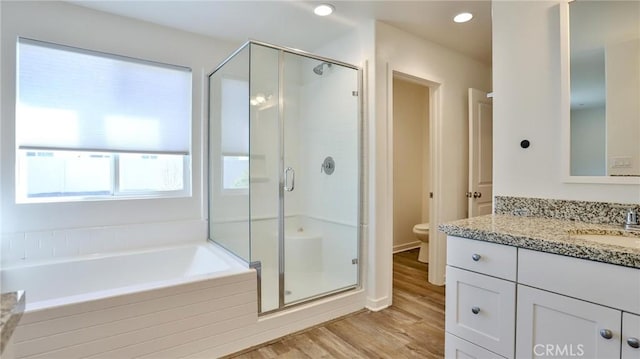 full bathroom with hardwood / wood-style flooring, toilet, vanity, and separate shower and tub