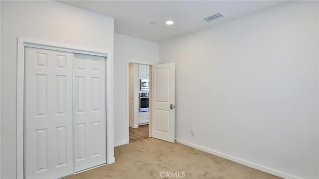 unfurnished bedroom featuring a closet and light carpet